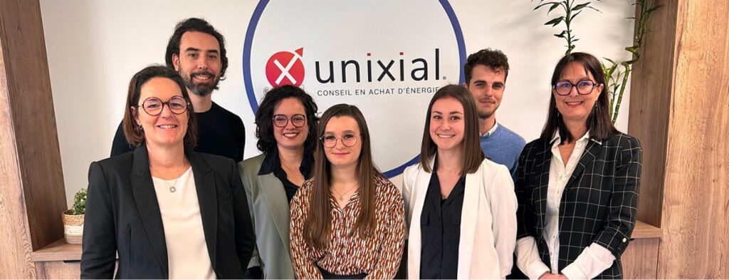 L'équipe d'Unixial devant le logo de l'entreprise dans leurs locaux.